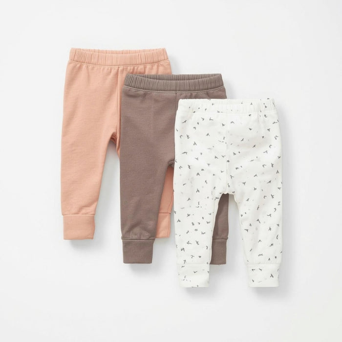 Three pairs of baby leggings in pink, brown, and white with a pattern on a light gray background