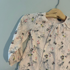 Close-up detail of Baby Gap blush pink blouse showing paradise bird print with floral pattern and gathered sleeves