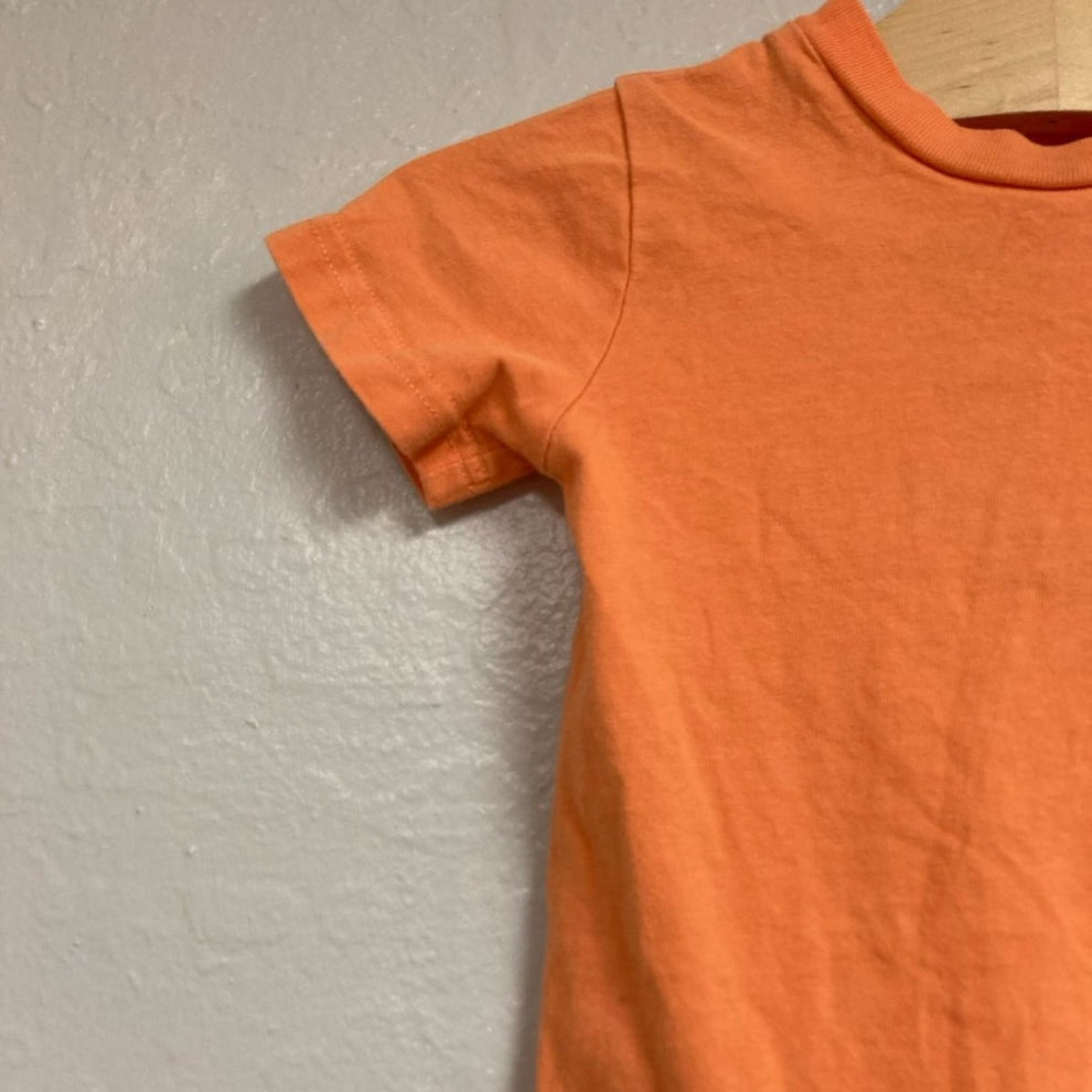 Close-up detail of Carhartt bright orange cotton short-sleeve bodysuit showing crew neckline and fabric texture for boys 18M