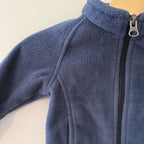 Close-up detail of Columbia navy blue fleece jacket showing YKK zipper, mock neck collar and plush fleece texture