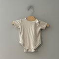 Front view of Goumi x Babylist cream organic cotton gender neutral short-sleeve bodysuit with shoulder snap and snap closure size 6-9 months
