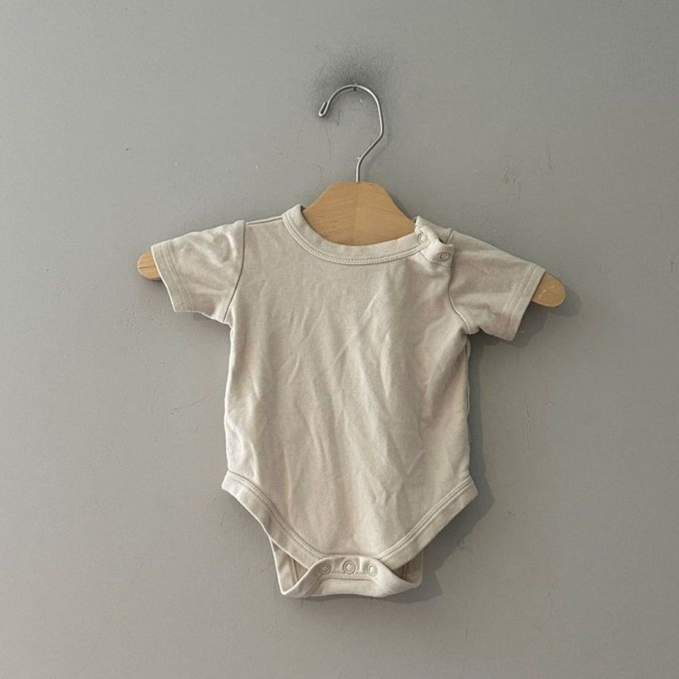 Front view of Goumi x Babylist cream organic cotton gender neutral short-sleeve bodysuit with shoulder snap and snap closure size 6-9 months