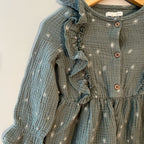 Close-up detail of Grayson Collective teal muslin dress showing white star embroidery, ruffled collar trim and wood buttons