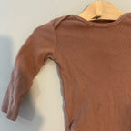 Close-up detail of H&M mocha brown ribbed long-sleeve baby bodysuit showing soft ribbed cotton fabric and shoulder stitching size 6-12 months