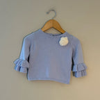 Front view of Janie and Jack periwinkle blue knit sweater with ruffle sleeves and white rosette pompom for girls 12-18 months