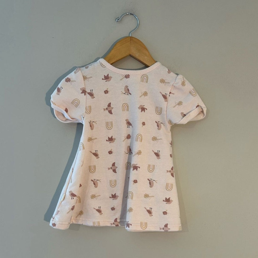 Back view of cream short-sleeve toddler dress with bird pattern and organic cotton fabric