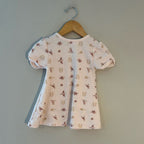 Back view of cream short-sleeve toddler dress with bird pattern and organic cotton fabric