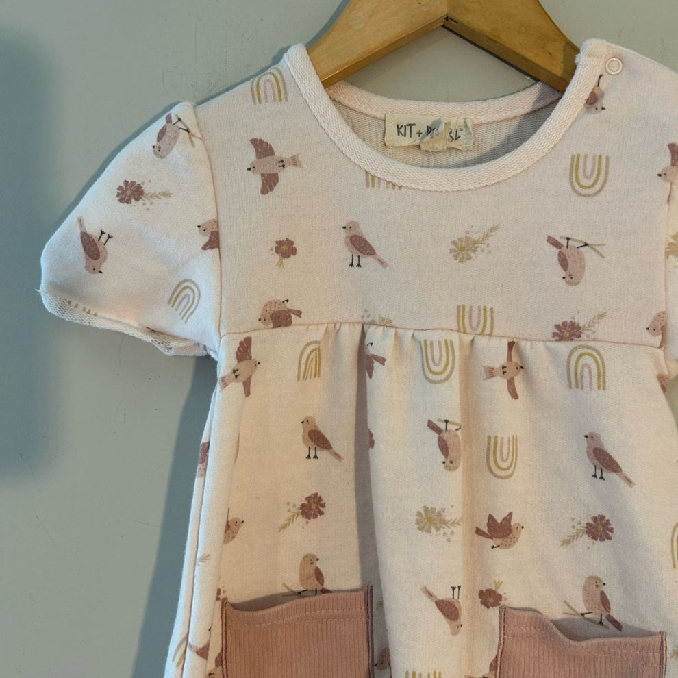 Close-up detail of Kit + Pearl dress neckline showing bird and rainbow print on organic cotton