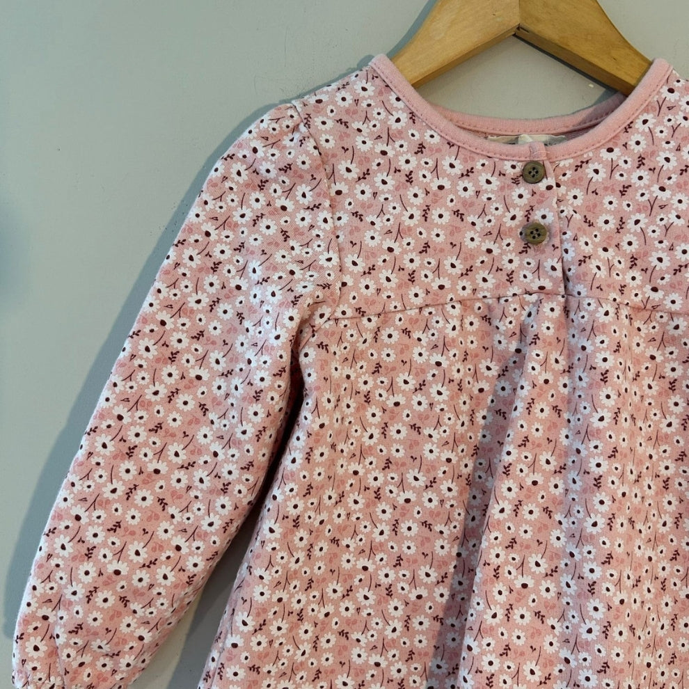 Close-up detail of Kit + Pearl pink floral dress showing daisy pattern, button neckline and gathered elastic sleeves