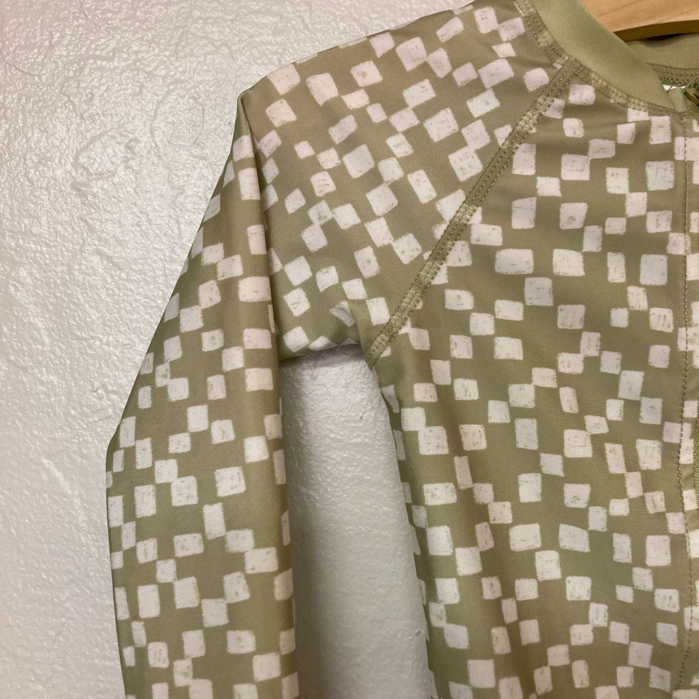 Close-up detail of Little Co. olive green rashguard showing checkered pattern and front zipper closure
