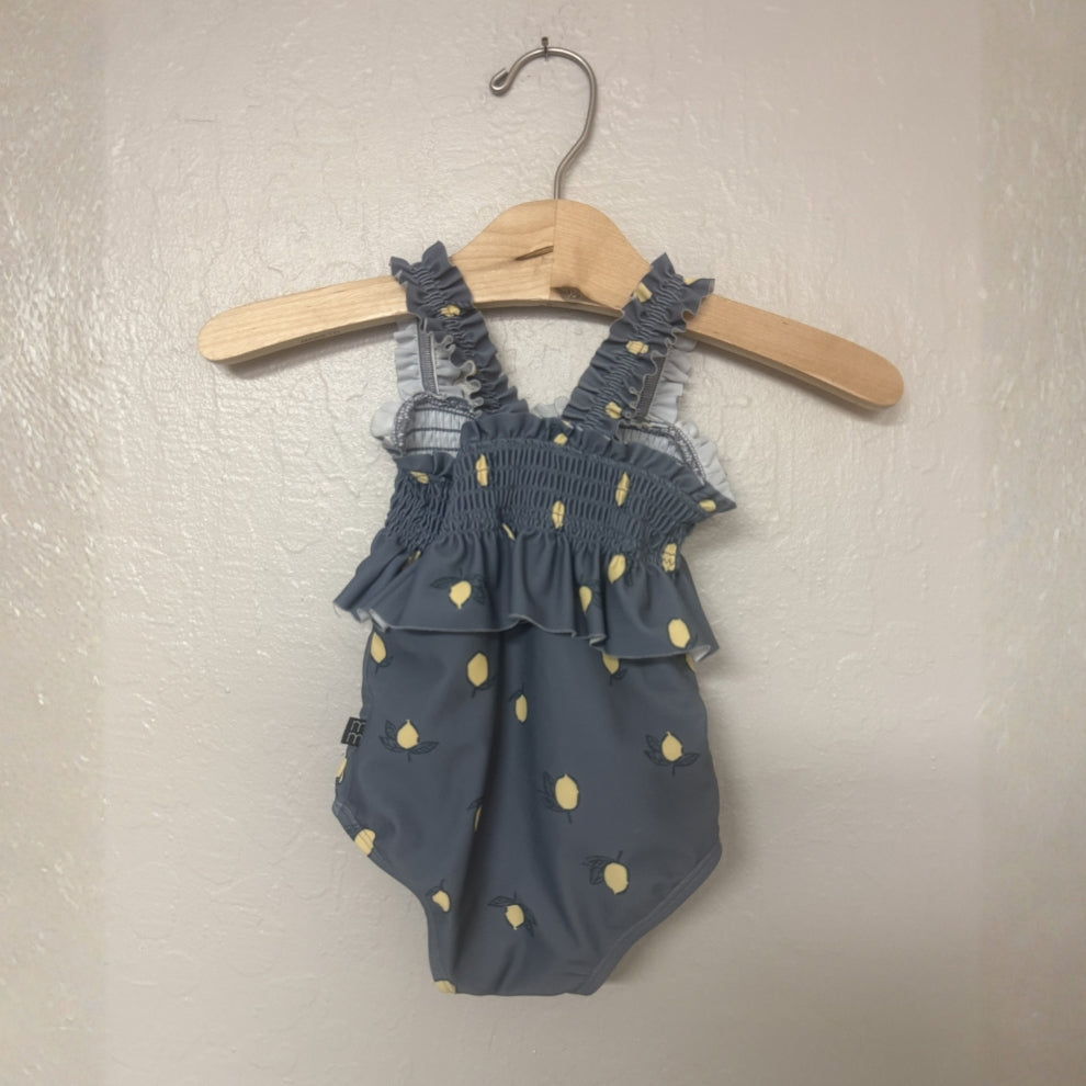 Back view of Modern Moments gray-blue one-piece swimsuit with lemon pattern and ruffle straps for baby girls