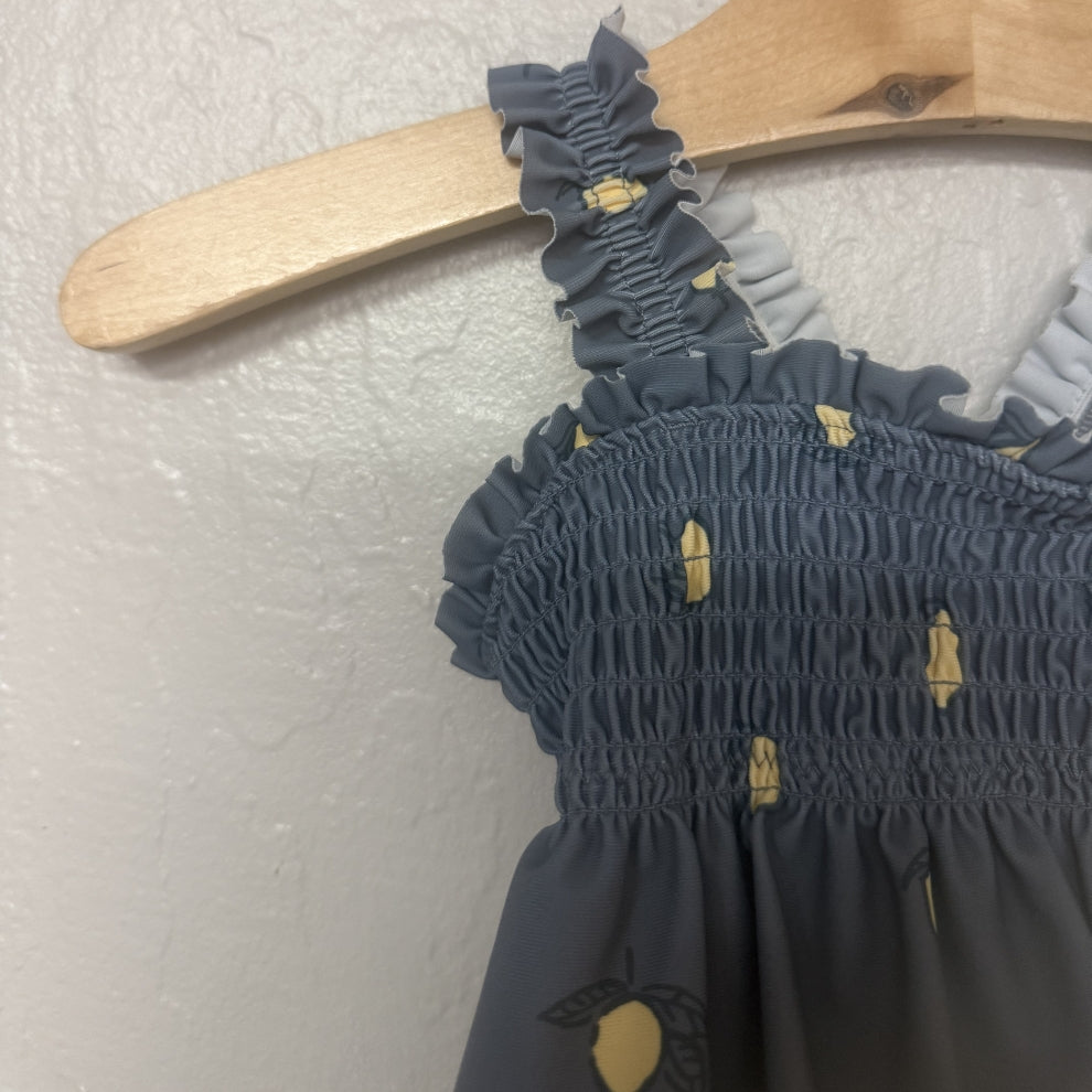 Close-up detail of Modern Moments swimsuit showing smocked elastic chest and ruffled shoulder straps with lemon print