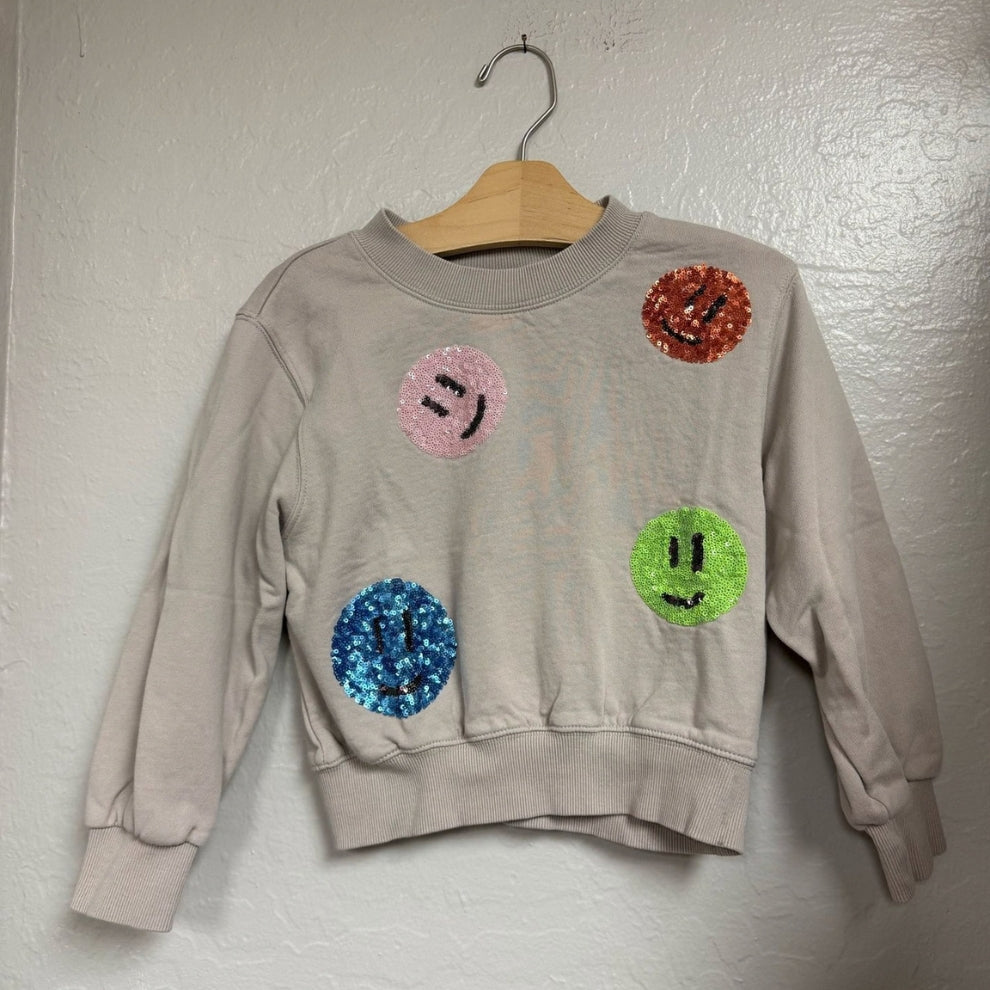 Front view of a Molo light gray girls’ sweatshirt in size 6Y (EU 116) with colorful sequin smiley face patches.