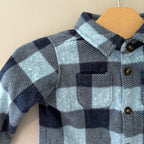 Close-up detail of Old Navy blue buffalo plaid fleece shacket showing chest pocket, dark buttons and collar for boys 6-12 months