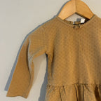 Close-up detail of Quincy Mae gold romper showing pointelle knit texture and ruffled collar