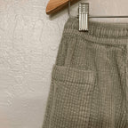 Close-up detail of Zara sage green corduroy pants showing front pocket and ribbed texture