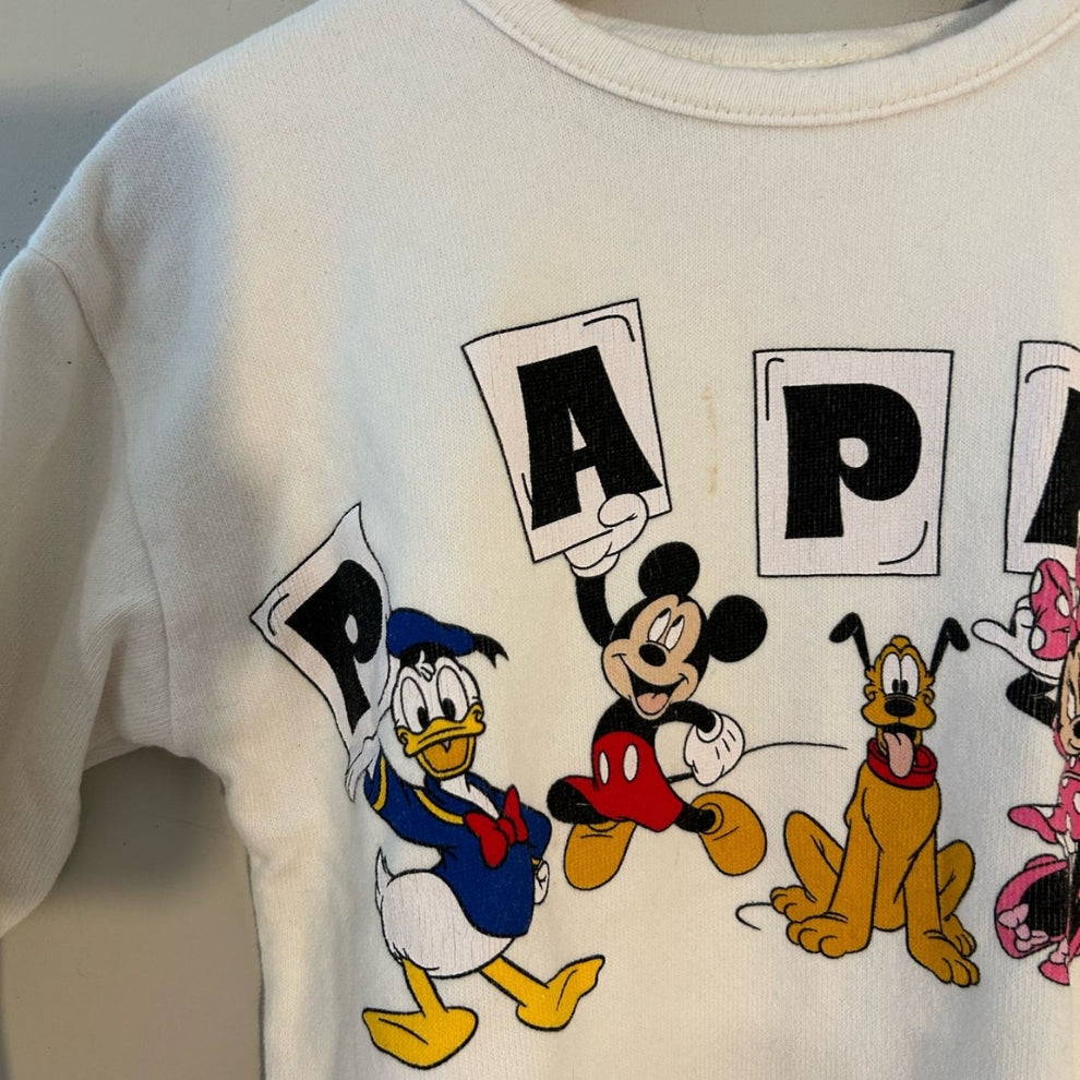 Close-up detail of Zara x Disney pullover showing Mickey Minnie Donald Pluto Daisy with Papa Te Quiero Spanish text letters