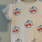 Close-up detail of Zara white girls tee showing all-over red cherry and teal "Favourite Cherries Always Together" circular text print, size 3Y
